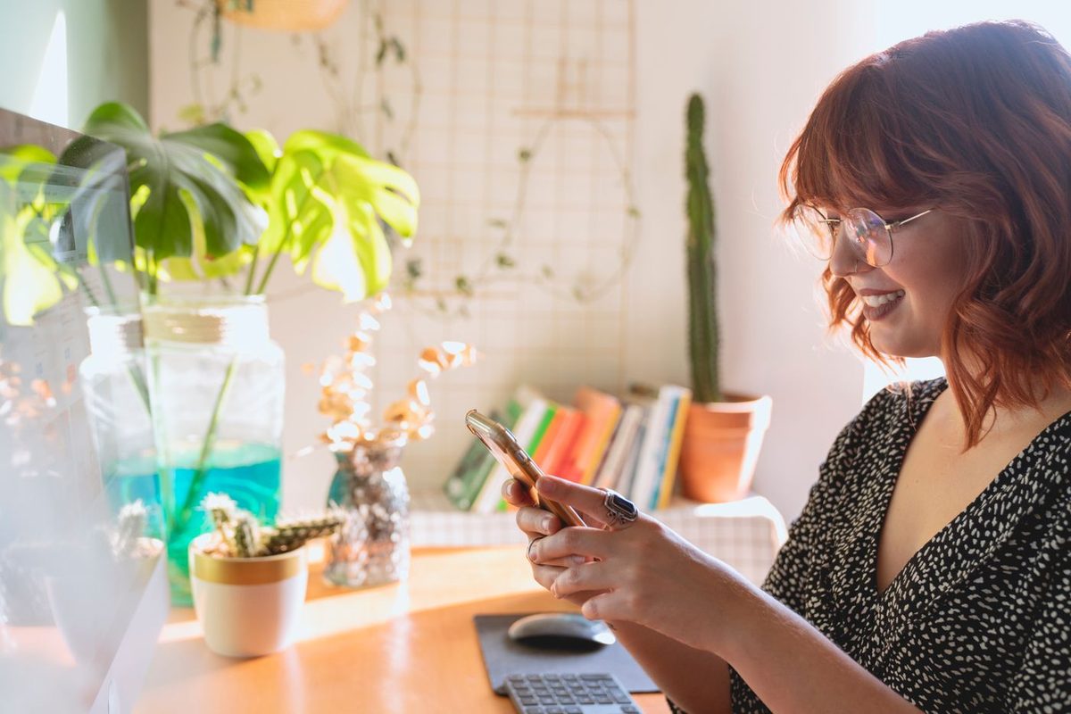 A woman smiling while reading a message on a dating app at home